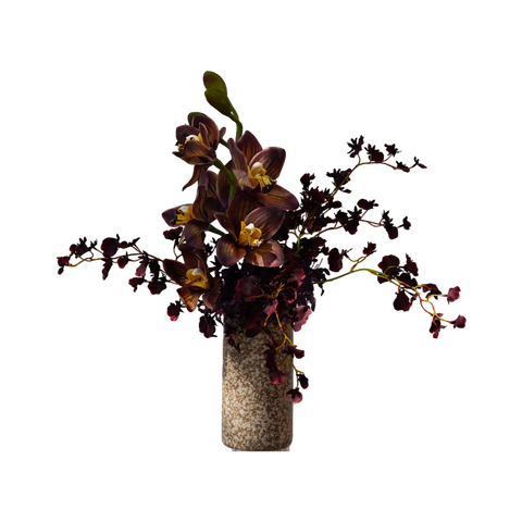 A dark burgundy and purple orchid floral arrangement with yellow accents, presented in a speckled beige stone cylinder vase against a solid white background.